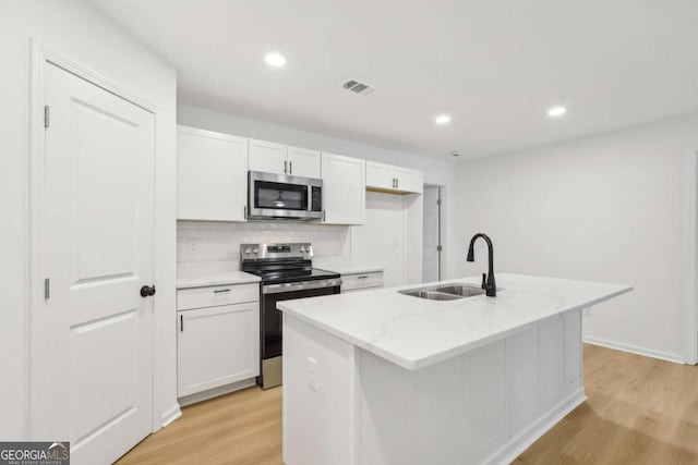 2765 Ocean Valley Dr, Atlanta, GA 30349 - kitchen featuring appliances with stainless steel finishes, a sink, light wood finished floors, white cabinets, and backsplash
