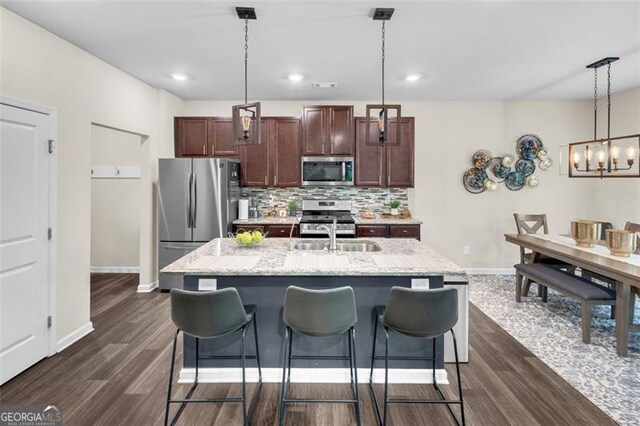 104 Auburn Xing, Auburn, GA 30011 - kitchen with appliances with stainless steel finishes, backsplash, dark wood-style flooring, an island with sink, and a breakfast bar
