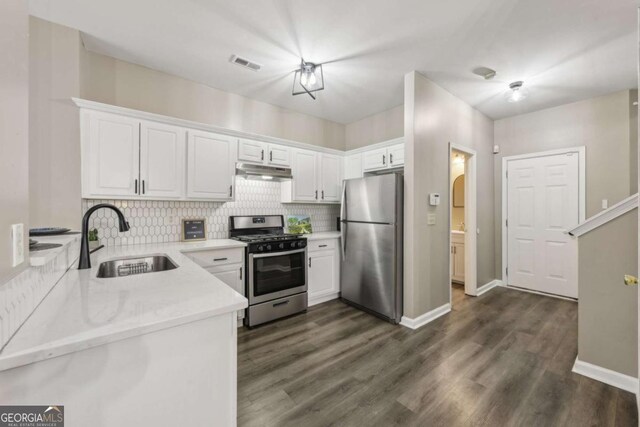 7077 Biltmore Trce, Lithonia, GA 30058 - kitchen with appliances with stainless steel finishes, under cabinet range hood, backsplash, white cabinetry, and dark wood-style flooring