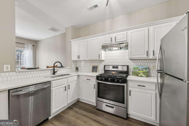 7077 Biltmore Trce, Lithonia, GA 30058 - kitchen featuring appliances with stainless steel finishes, under cabinet range hood, light countertops, white cabinetry, and backsplash