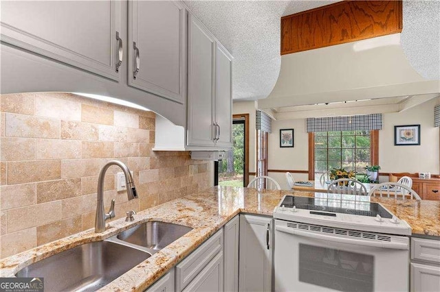 3472 Honeycomb Dr SE, Conyers, GA 30094 - kitchen featuring white range with electric stovetop, a sink, decorative backsplash, light stone counters, and a peninsula