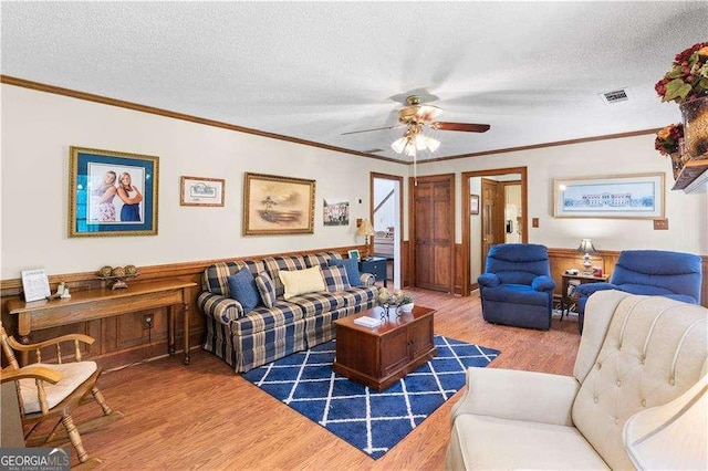 3472 Honeycomb Dr SE, Conyers, GA 30094 - living room with wood finished floors, a textured ceiling, a ceiling fan, ornamental molding, and a wainscoted wall