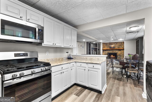 630 Buttercup Trce, Alpharetta, GA 30022 - kitchen with appliances with stainless steel finishes, light wood-style floors, a peninsula, white cabinetry, and a drop ceiling