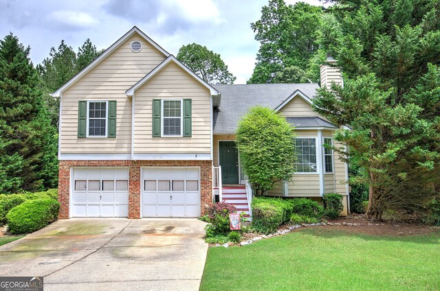 1047 Taso Trl, Acworth, GA 30101 - split level home featuring an attached garage, driveway, a front yard, brick siding, and a chimney