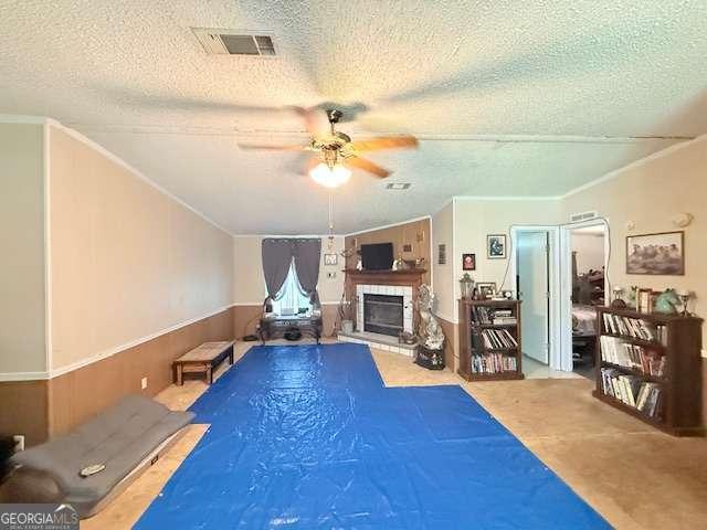 250 River Trce, Hahira, GA 31632 - interior space featuring ceiling fan, a textured ceiling, a fireplace with raised hearth, crown molding, and a wainscoted wall
