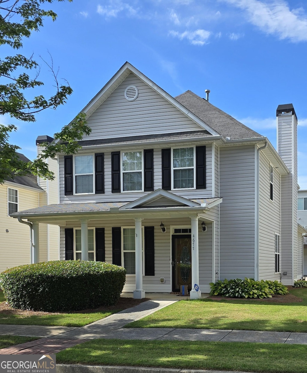 view of front of property featuring a porch, a chimney, and a front yard
