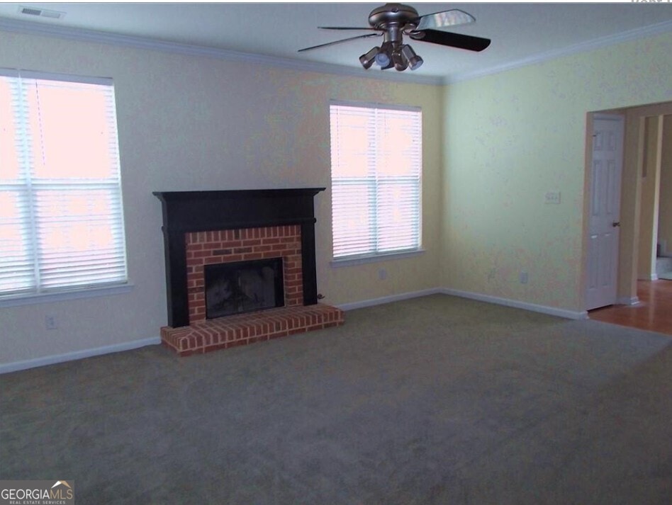 unfurnished living room featuring ornamental molding, ceiling fan, carpet floors, and healthy amount of natural light