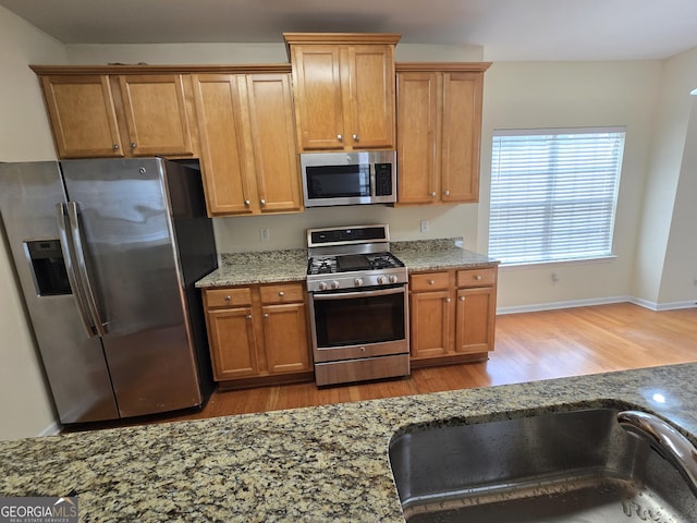 4677 Liberty Square Dr, Acworth, GA 30101 - kitchen with appliances with stainless steel finishes, light wood-type flooring, light stone countertops, and brown cabinets