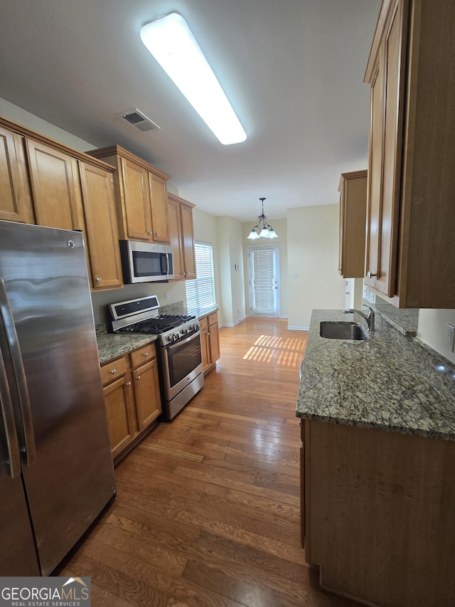 4677 Liberty Square Dr, Acworth, GA 30101 - kitchen featuring appliances with stainless steel finishes, dark wood-style floors, dark stone counters, pendant lighting, and brown cabinetry