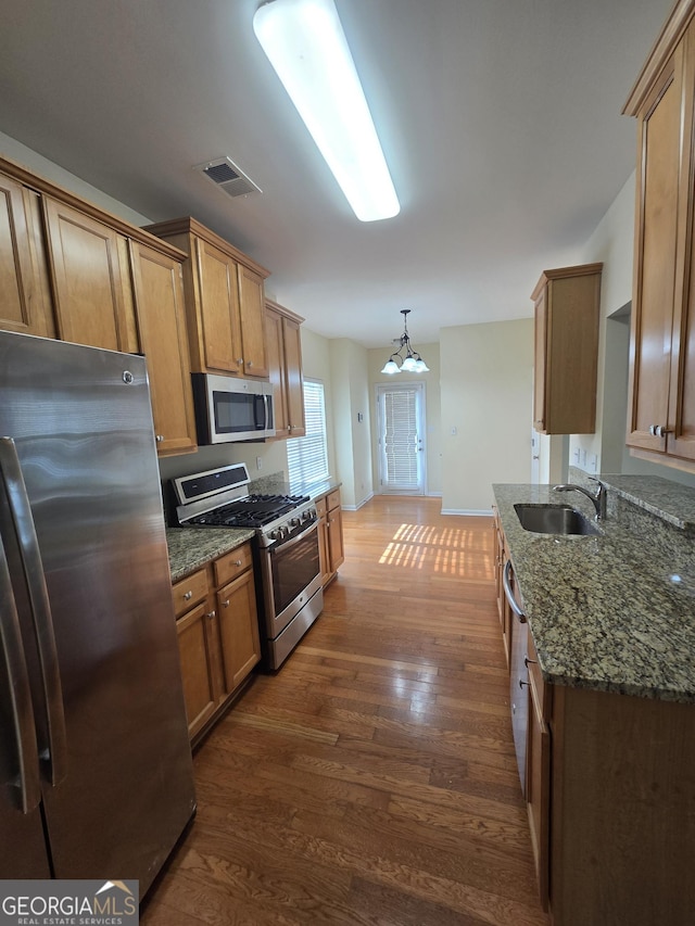 4677 Liberty Square Dr, Acworth, GA 30101 - kitchen featuring appliances with stainless steel finishes, dark wood-type flooring, dark stone counters, brown cabinets, and a chandelier