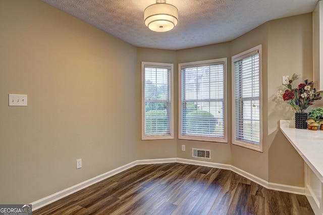 221 Ashley Oaks Dr, Mcdonough, GA 30253 - unfurnished dining area featuring dark wood-type flooring, baseboards, healthy amount of natural light, and a textured ceiling