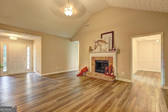 221 Ashley Oaks Dr, Mcdonough, GA 30253 - unfurnished living room with wood finished floors, a brick fireplace, high vaulted ceiling, and baseboards