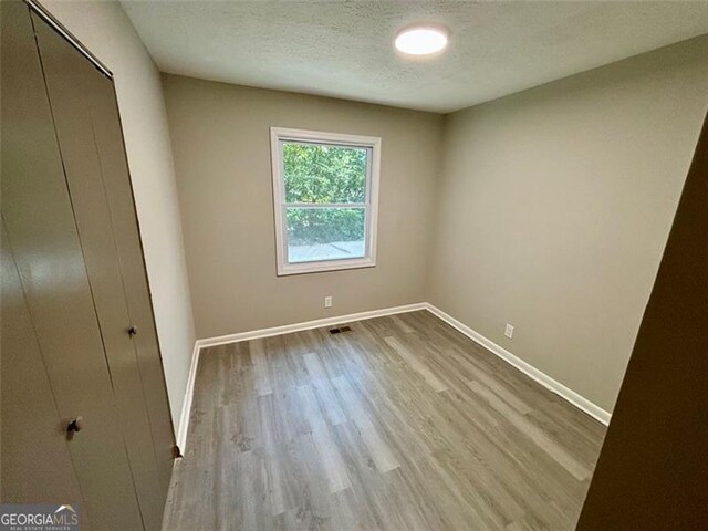 2489 Hillside Dr, Macon, GA 31206 - unfurnished bedroom with wood finished floors, baseboards, a closet, and a textured ceiling