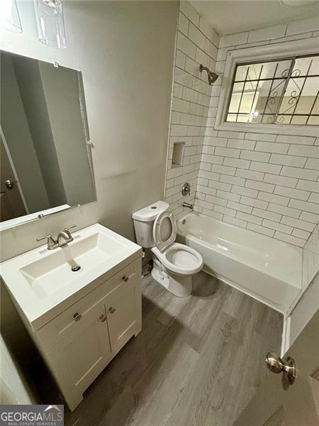 2489 Hillside Dr, Macon, GA 31206 - bathroom with wood finished floors, toilet, shower / bathtub combination, and vanity