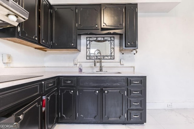 1293 Courtland Ave, Macon, GA 31204 - kitchen with under cabinet range hood, light countertops, a sink, light marble finish flooring, and dark cabinets