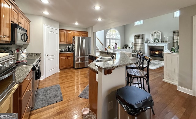 297 Old Clarkesville Mill Rd, Clarkesville, GA 30523 - kitchen with appliances with stainless steel finishes, a sink, a breakfast bar area, wood finished floors, and brown cabinets