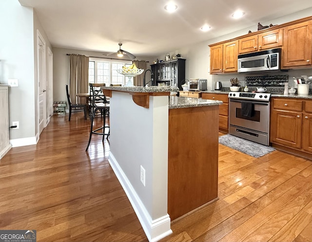 297 Old Clarkesville Mill Rd, Clarkesville, GA 30523 - kitchen with appliances with stainless steel finishes, a breakfast bar area, light wood-style floors, brown cabinets, and recessed lighting