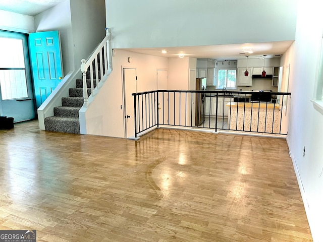 1040 Forest E Dr, Stone Mountain, GA 30088 - unfurnished living room with wood finished floors, a high ceiling, a sink, and stairs