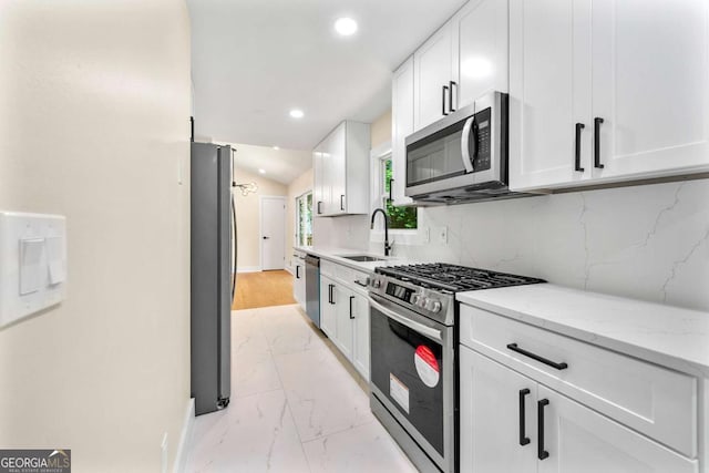 4043 Chedworth Way, Stone Mountain, GA 30083 - kitchen with stainless steel appliances, a sink, light marble finish floors, white cabinetry, and baseboards