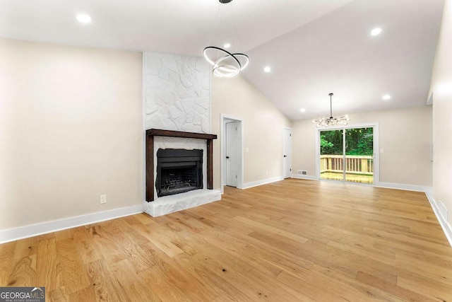 4043 Chedworth Way, Stone Mountain, GA 30083 - unfurnished living room featuring a chandelier, baseboards, a stone fireplace, light wood finished floors, and lofted ceiling