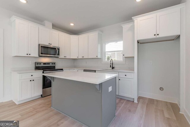 3110 Granada Way, Gainesville, GA 30506 - kitchen featuring stainless steel appliances, light wood-style floors, a kitchen island, white cabinets, and light countertops