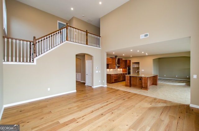 8555 Scenic Ridge Way, Ball Ground, GA 30107 - unfurnished living room with arched walkways, light wood-style flooring, a towering ceiling, and recessed lighting