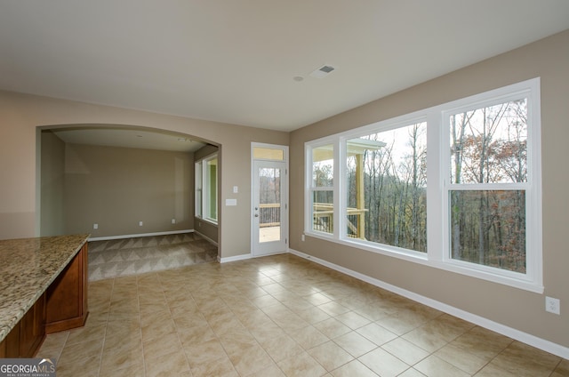 8555 Scenic Ridge Way, Ball Ground, GA 30107 - unfurnished living room with arched walkways, baseboards, and light tile patterned floors