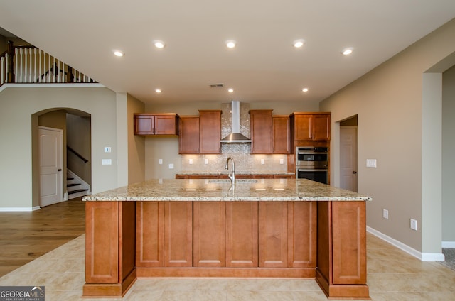 8555 Scenic Ridge Way, Ball Ground, GA 30107 - kitchen with wall chimney exhaust hood, double oven, a spacious island, light stone counters, and backsplash