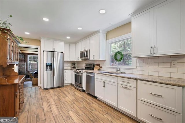 184 Rambo Pl SW, Marietta, GA 30064 - kitchen with stainless steel appliances, a sink, backsplash, white cabinetry, and light stone counters