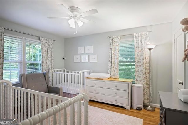 184 Rambo Pl SW, Marietta, GA 30064 - bedroom featuring light wood-style floors, a nursery area, a ceiling fan, and baseboards