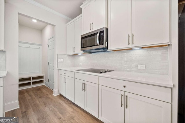 724 Broken Arrow, Waleska, GA 30183 - kitchen featuring stainless steel microwave, black electric stovetop, light countertops, white cabinetry, and crown molding