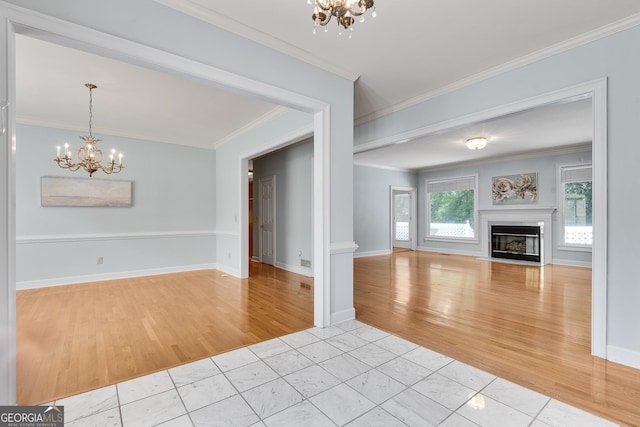 1285 Rivershyre Pkwy, Lawrenceville, GA 30043 - unfurnished living room with a chandelier, light wood finished floors, crown molding, a fireplace with flush hearth, and baseboards