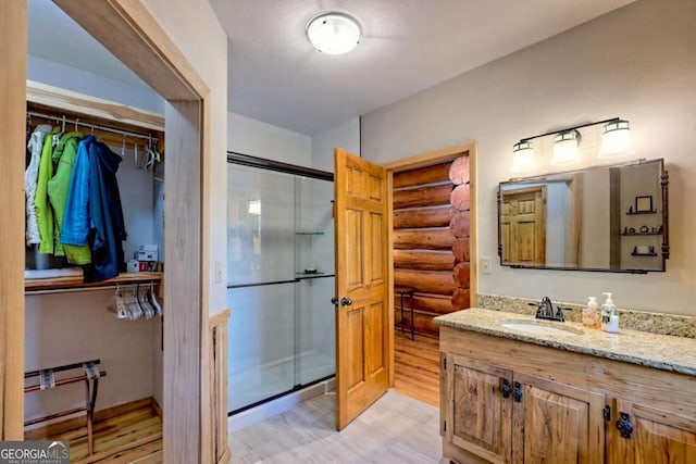 6487 W Old Highway 64 W, Warne, NC 28909 - bathroom featuring wood finished floors, a shower stall, rustic walls, vanity, and a walk in closet