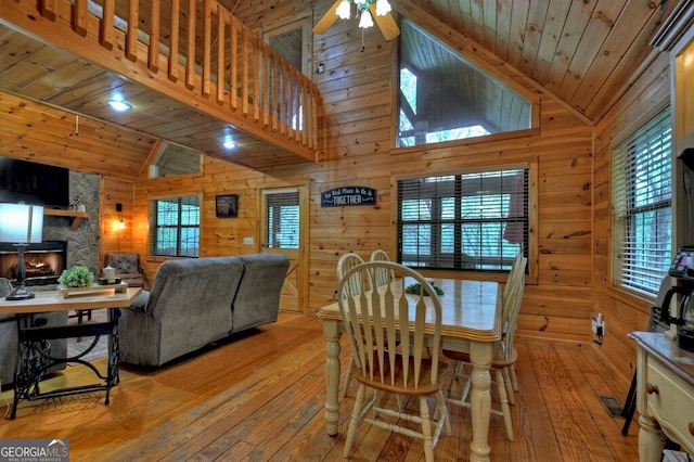 294 Oakwood Trl, Mineral Bluff, GA 30559 - dining area featuring light wood-style floors, a ceiling fan, wooden walls, a stone fireplace, and wooden ceiling