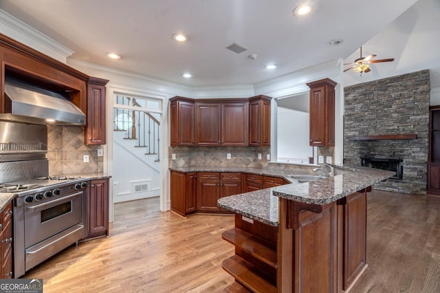 5620 Barnett Shoals Rd, Athens, GA 30605 - kitchen featuring stainless steel range, open shelves, wall chimney range hood, a stone fireplace, and ceiling fan