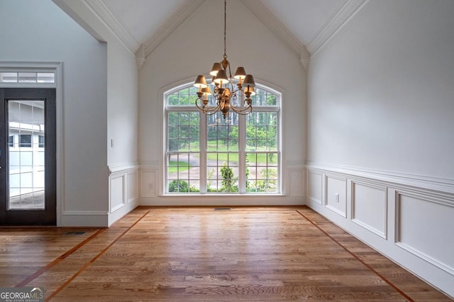 5620 Barnett Shoals Rd, Athens, GA 30605 - unfurnished dining area with a chandelier, wood finished floors, vaulted ceiling, a wainscoted wall, and a decorative wall