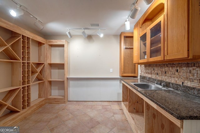 5620 Barnett Shoals Rd, Athens, GA 30605 - kitchen featuring rail lighting, wainscoting, tasteful backsplash, glass insert cabinets, and brown cabinets