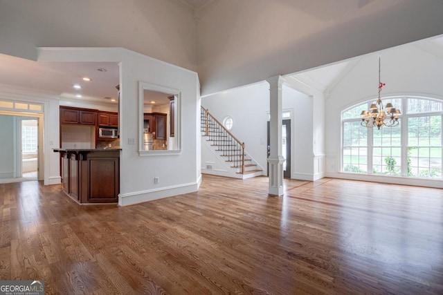5620 Barnett Shoals Rd, Athens, GA 30605 - unfurnished living room with wood finished floors, a chandelier, stairs, and high vaulted ceiling