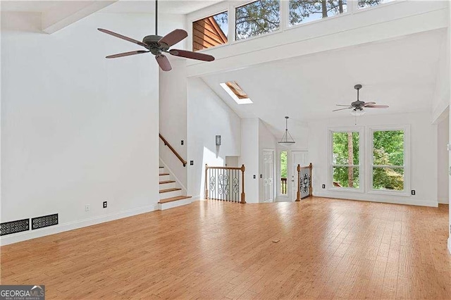 3007 Manning Dr, Marietta, GA 30062 - unfurnished living room with high vaulted ceiling, ceiling fan, a skylight, wood finished floors, and stairs