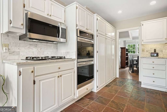 3734 Powers Ferry Rd NW, Atlanta, GA 30342 - kitchen with stainless steel appliances, backsplash, white cabinets, dark stone finish flooring, and recessed lighting