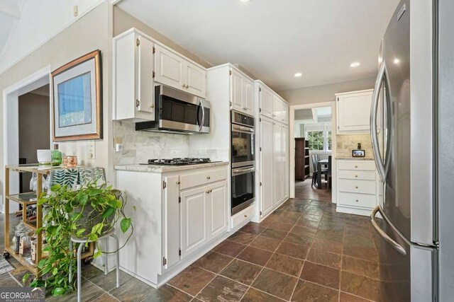 3734 Powers Ferry Rd NW, Atlanta, GA 30342 - kitchen featuring appliances with stainless steel finishes, tasteful backsplash, light countertops, white cabinetry, and recessed lighting