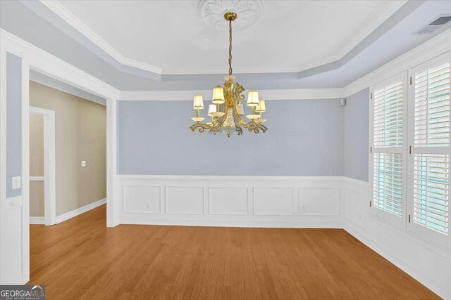 2021 Cockrell Pointe NW, Kennesaw, GA 30152 - unfurnished dining area with a tray ceiling, a chandelier, wood finished floors, wainscoting, and ornamental molding