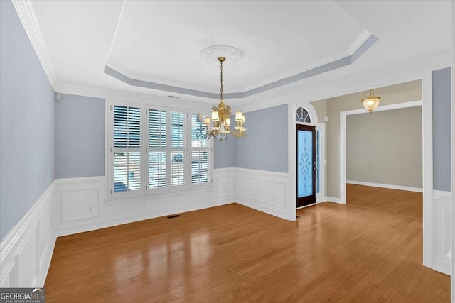 2021 Cockrell Pointe NW, Kennesaw, GA 30152 - unfurnished room featuring a chandelier, a raised ceiling, wood finished floors, wainscoting, and crown molding