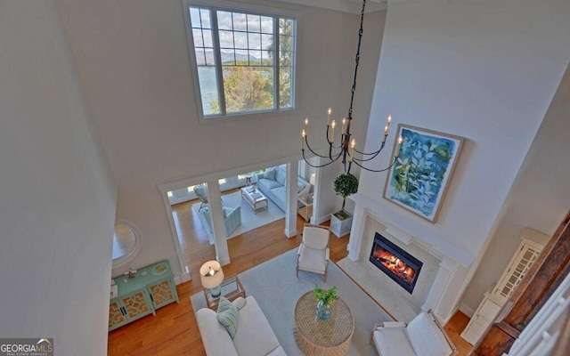 1951 Island View Dr, Hiawassee, GA 30546 - living room featuring a towering ceiling, a glass covered fireplace, wood finished floors, and a chandelier