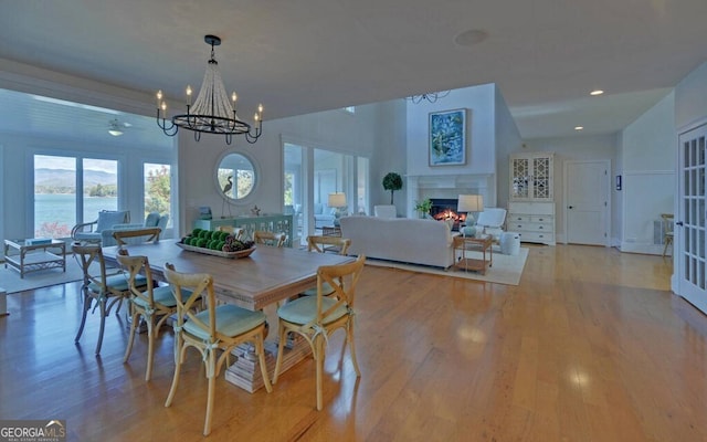 1951 Island View Dr, Hiawassee, GA 30546 - dining room featuring a lit fireplace, light wood-type flooring, a chandelier, and recessed lighting