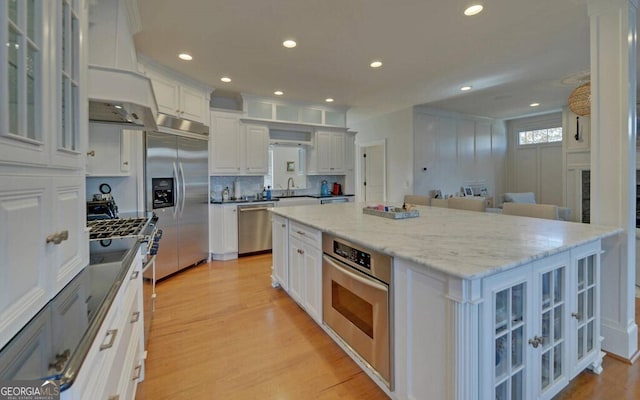 1951 Island View Dr, Hiawassee, GA 30546 - kitchen featuring appliances with stainless steel finishes, light wood-type flooring, white cabinetry, custom exhaust hood, and recessed lighting