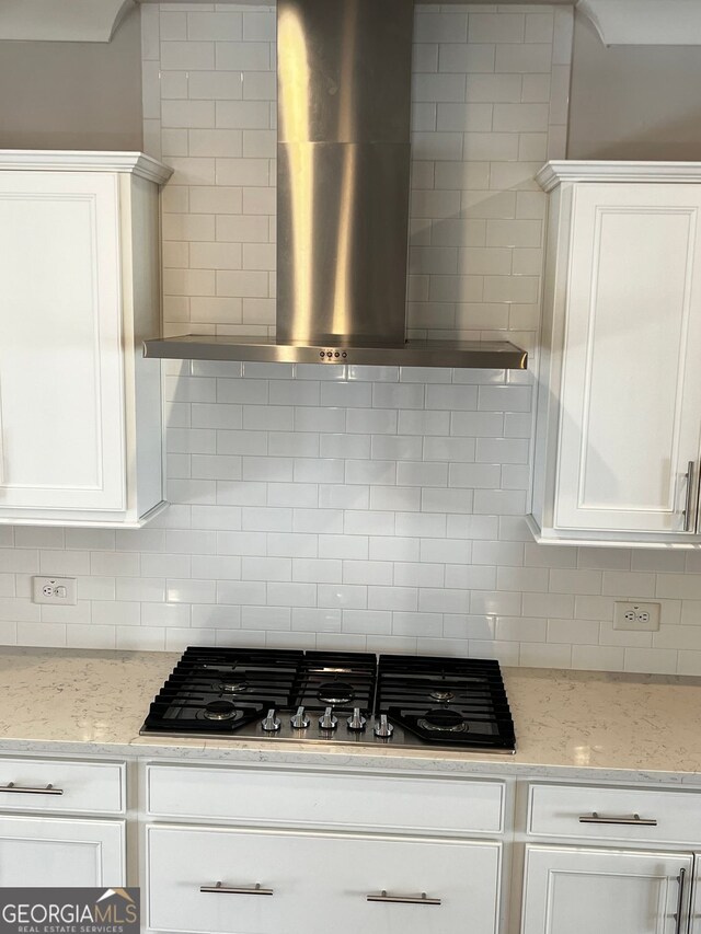 996 Layton Dr, Buford, GA 30518 - kitchen featuring wall chimney exhaust hood, stainless steel gas stovetop, tasteful backsplash, white cabinetry, and light stone counters