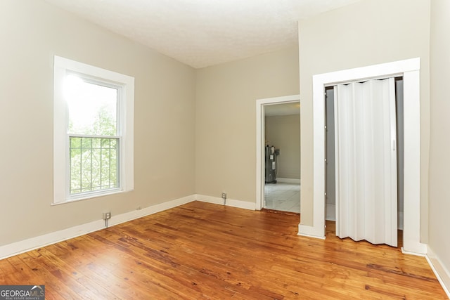 404 N 15th St, Griffin, GA 30223 - unfurnished bedroom with light wood-type flooring, baseboards, a closet, and electric water heater