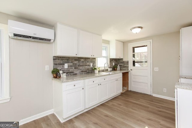 272 Old Sudie Rd, Hiram, GA 30141 - kitchen with a wall unit AC, white cabinets, backsplash, light wood-style flooring, and light stone countertops