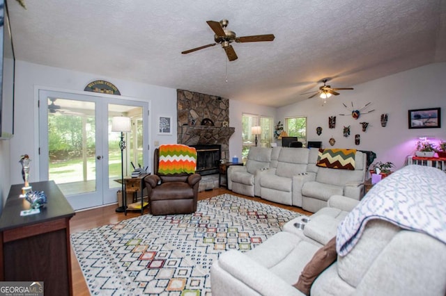 7358 S Mitchell Ct, Villa Rica, GA 30180 - living area with ceiling fan, french doors, a textured ceiling, wood finished floors, and a stone fireplace